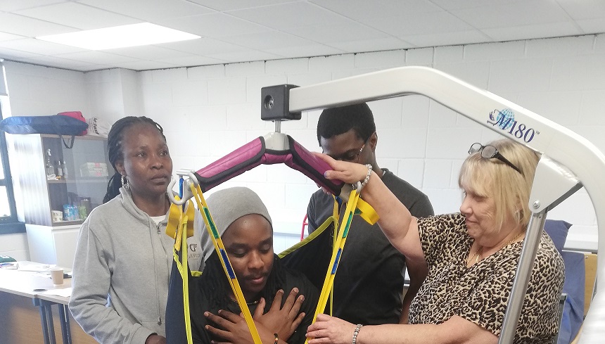 Care staff practising safe hoist techniques during training in a home setting